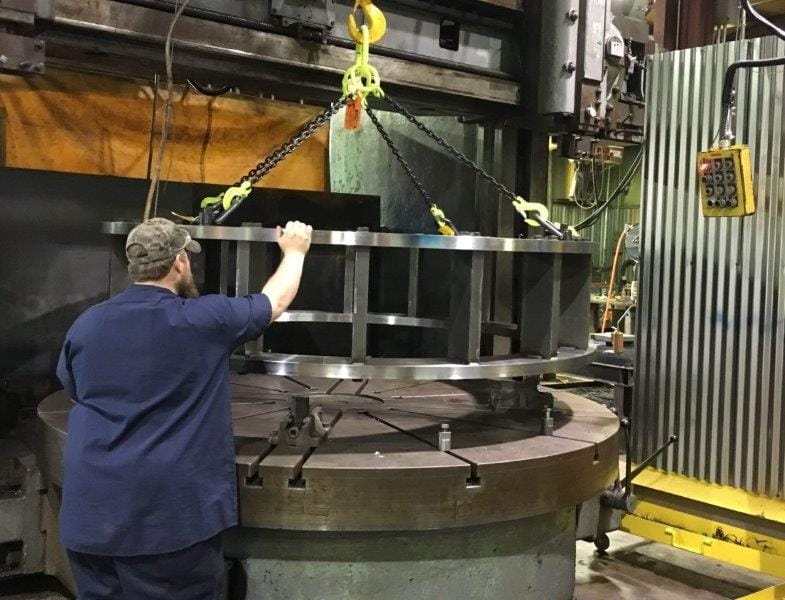 A stator retention frame being craned onto the 120 inch vertical turret lathe